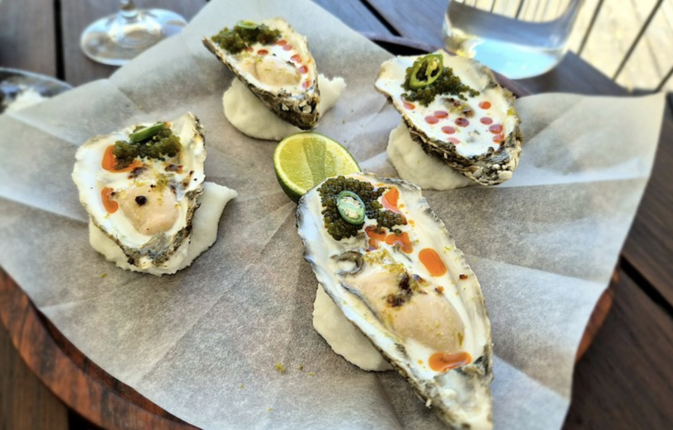 Four oysters at Chef's Warehouse at Beau Constantia — dressed with green-strawberry granita, salmon roe, jalapeño and lime, on the wine-bar deck