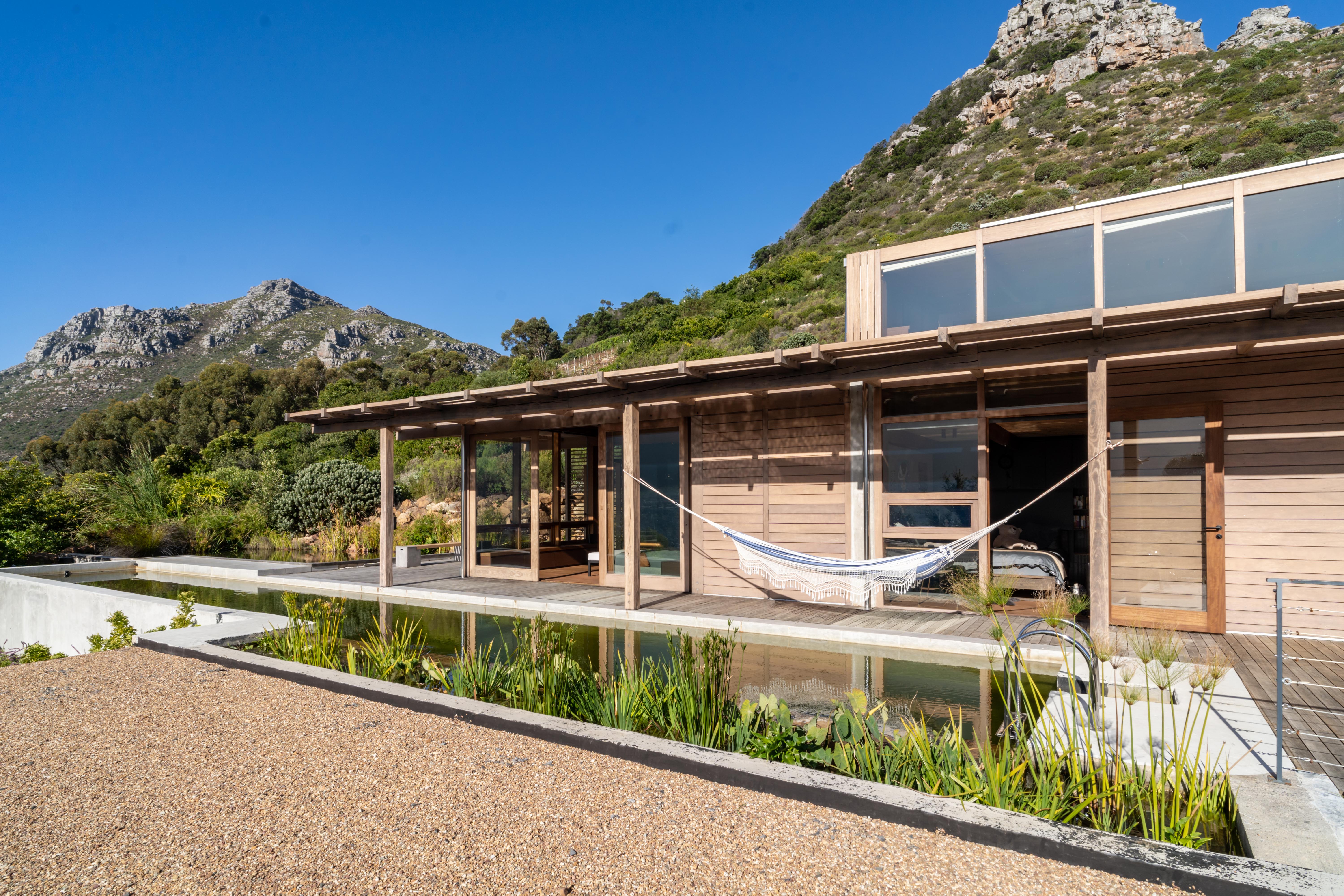 The exterior of the Grotto.CapeTown house at golden hour — built into the granite slope of Skoorsteenberg