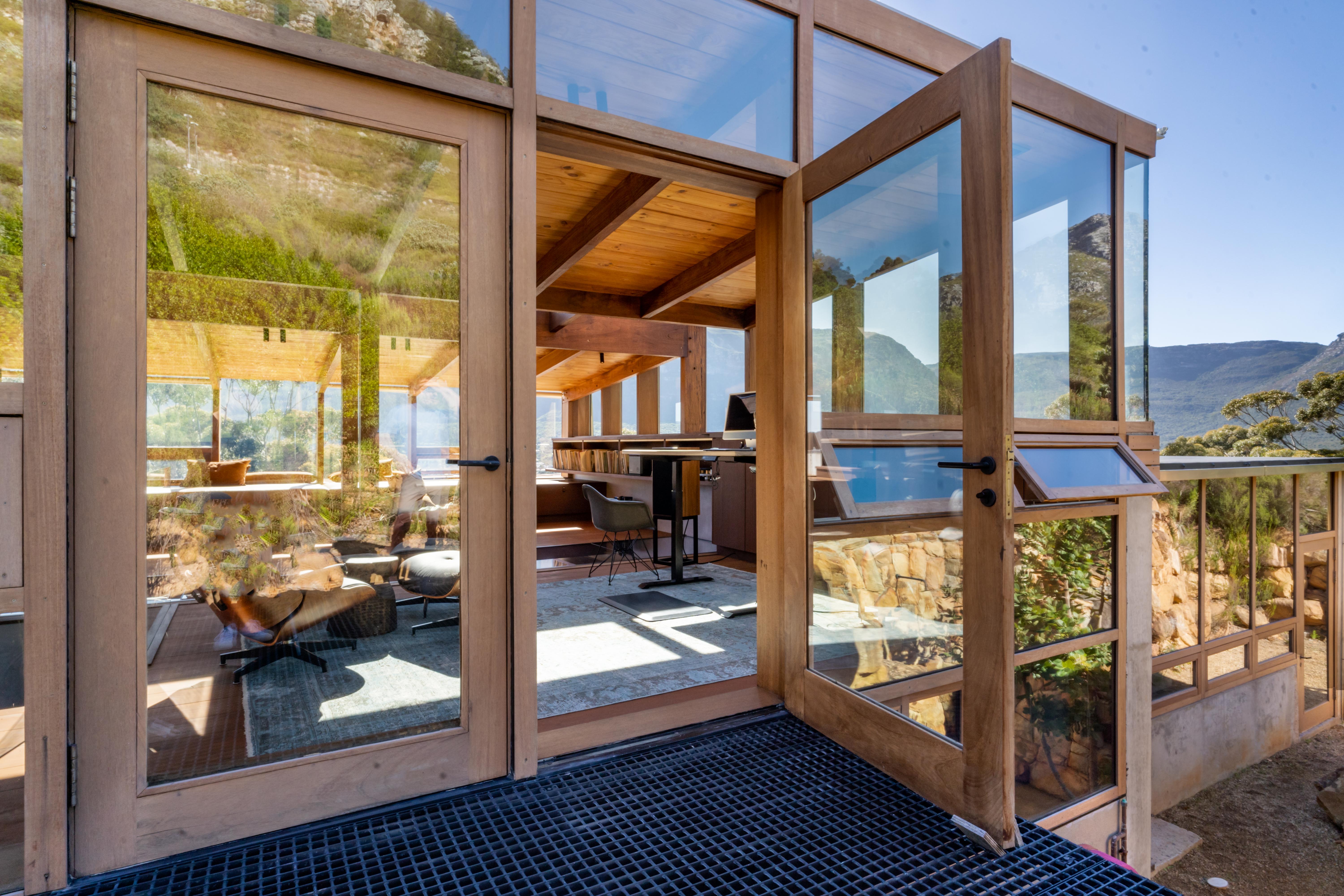 The threshold of the house — Iroko deck meeting glass sliding doors, Saligna pine slats above